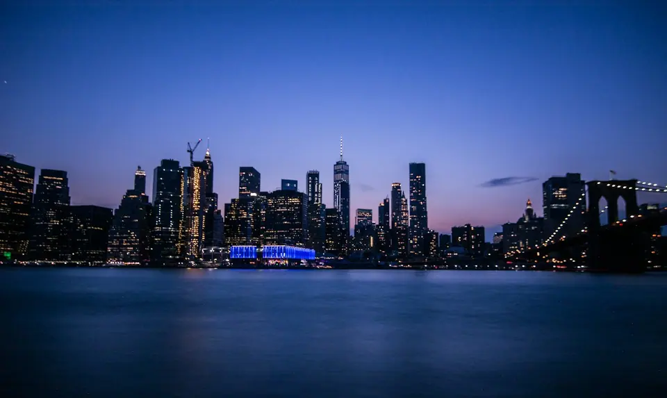 Manhattan skyline and Brooklyn Bridge across the East River at dusk